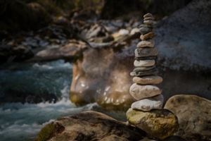 Piled up pebbles in front of river rock
