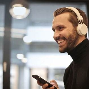 Mensch mit Kopfhörern steht für den wachsenden Hörbuchmarkt und Audio-Alltag