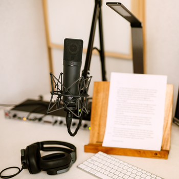 Professional Neumann U87 microphone, DBX 286s preamp, and a script on a wooden stand in the recording studio.