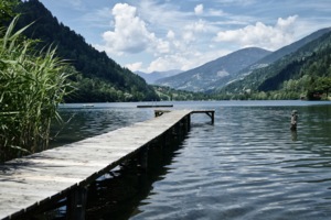 Blick auf Holzsteg, der vor Bergpanorama ins Wasser führt