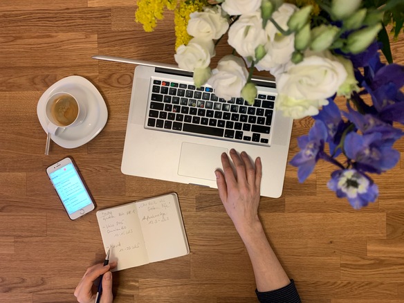Stilleben mit Laptop, Blumenstrauß, Espresso, Handy und Notizbuch
