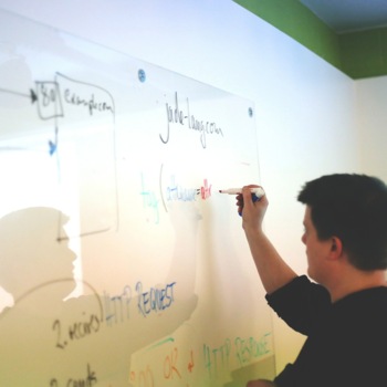 A young man writes formulas on a white board