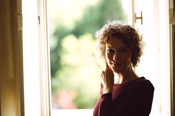 Blick bei Dämmerlicht auf Ann Vielhaben vor geöffnetem Fenster