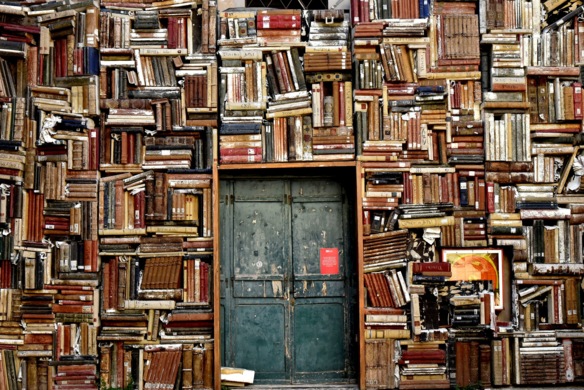 Dunkelgrüne Tür inmitten einer vollen Bücherwand