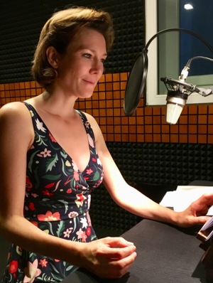 Ann in Sommerkleid vor Mikrofon in Studio, einen Text gestaltend