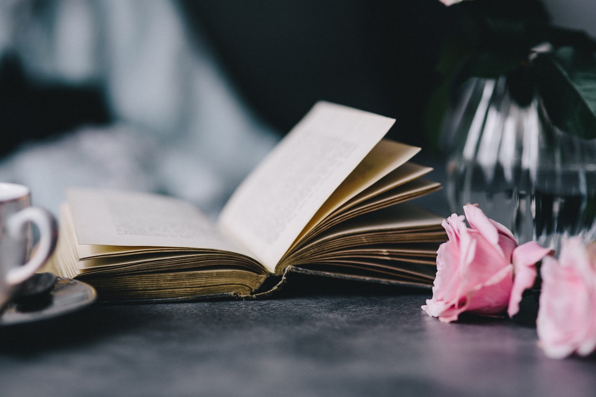 Stillleben mit Buch und Rose auf einer Tischplatte