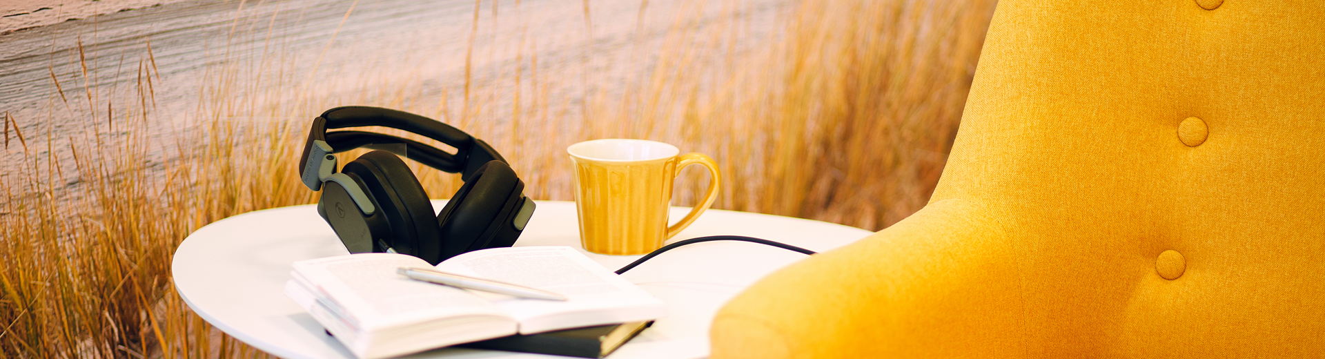 Studiolounge mit gelbem Sessel und einem weißem Beistelltisch, auf dem Kopfhörer liegen