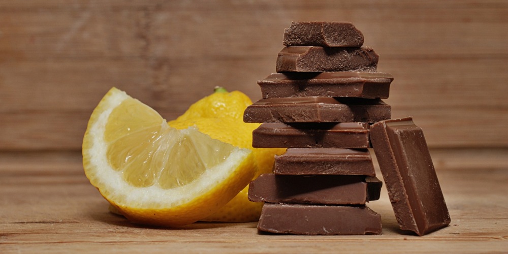 Schokoladenstücke und Zitronenscheiben auf Holzplatte